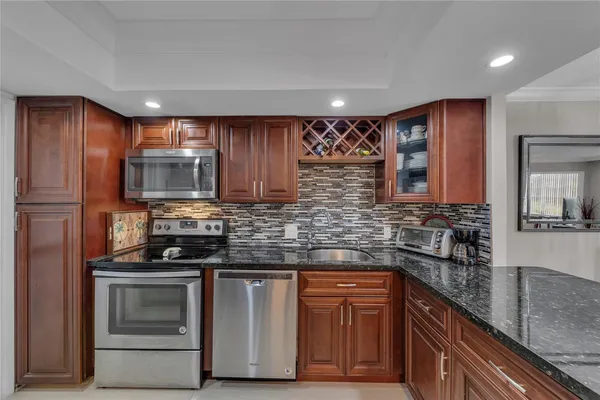 a kitchen with stainless steel appliances granite countertop wooden cabinets and a stove top oven