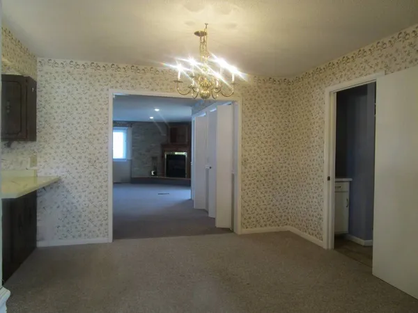 a view of a hallway to room with a chandelier