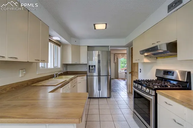 a kitchen with granite countertop a stove a sink and a refrigerator