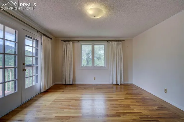 an empty room with wooden floor and windows