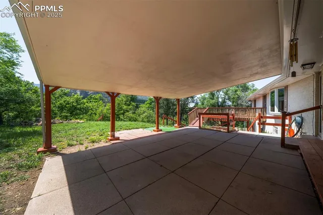a patio with table and chairs and floor to ceiling window