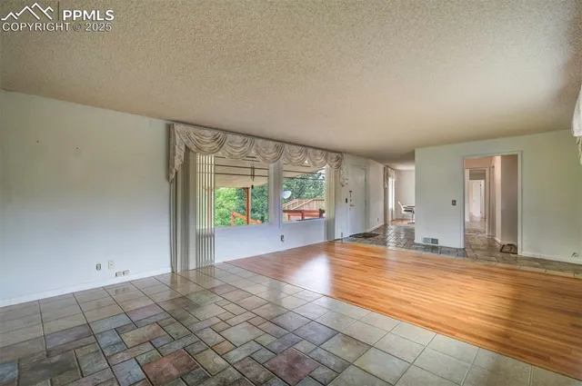 a view of an empty room with window and wooden floor