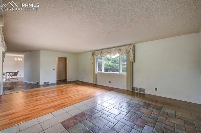 a view of an empty room with window and wooden floor