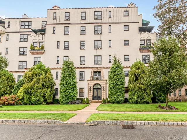 a view of a building with a yard and large trees