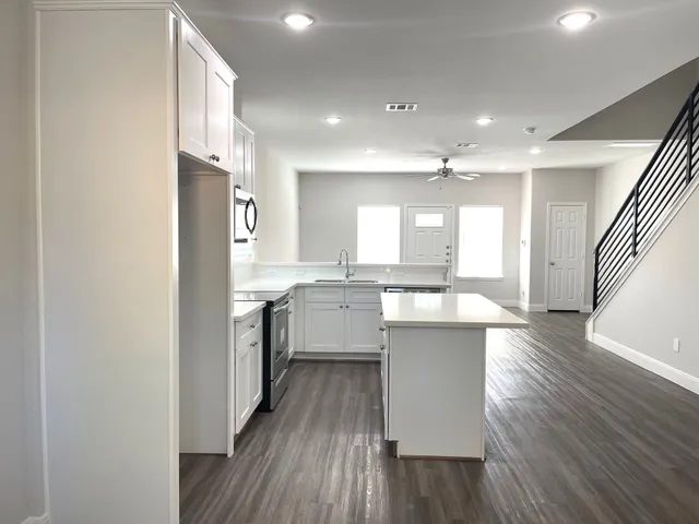 a large kitchen with a center island wooden floor stainless steel appliances and windows