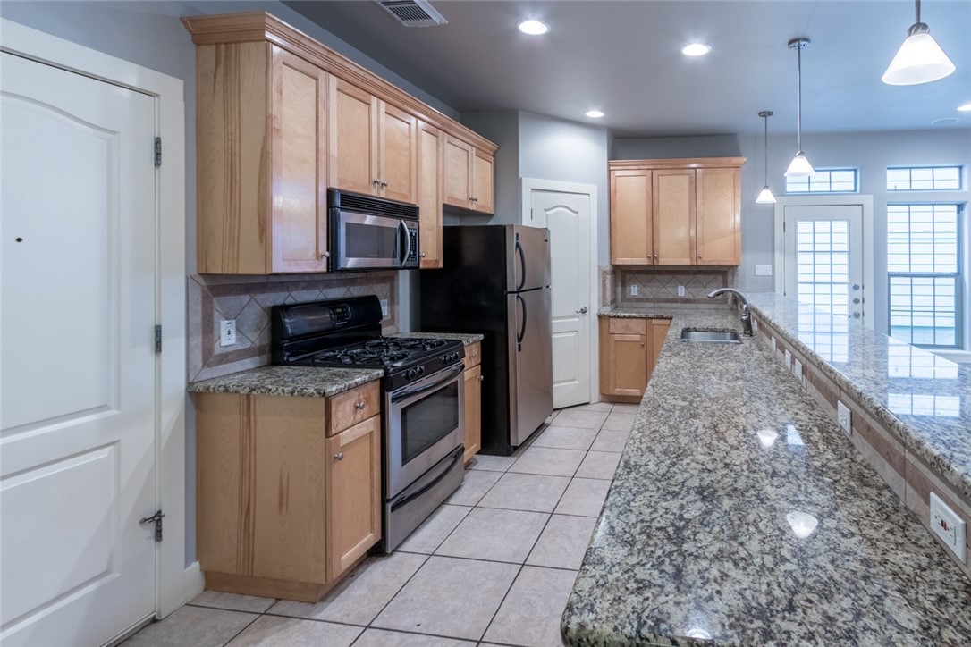 306 East 34th Street, Unit A Austin, TX 78705 - Photo 4 of 25 a kitchen with stainless steel appliances granite countertop a refrigerator a stove top oven and a sink
