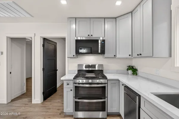 a kitchen with stainless steel appliances a stove a microwave and wooden floors