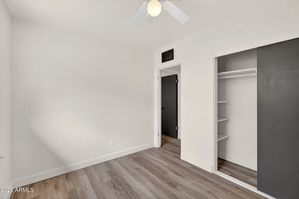 an empty room with wooden floor chandelier fan and windows