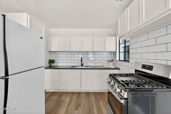 a kitchen with a refrigerator a stove and white cabinets