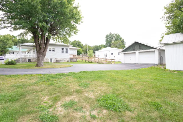 a view of a house with a big yard and large tree