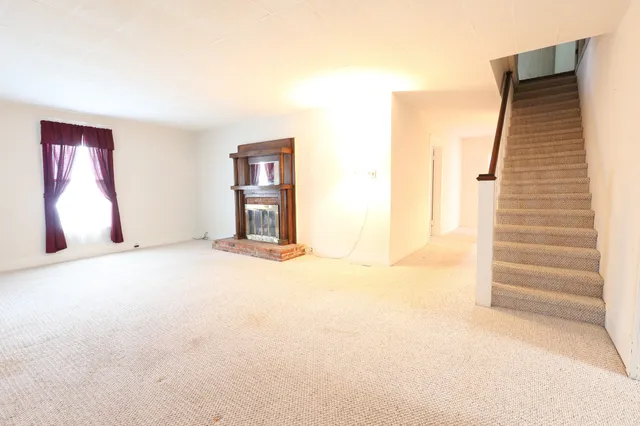 a view of an empty room with stairs and a window