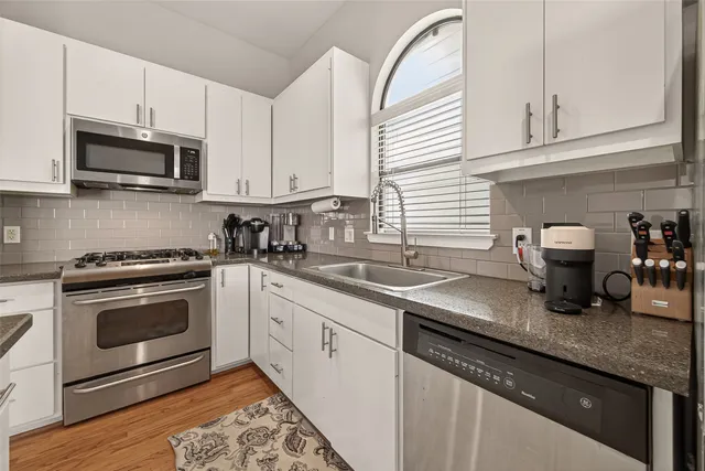 a kitchen with granite countertop a sink stainless steel appliances and cabinets