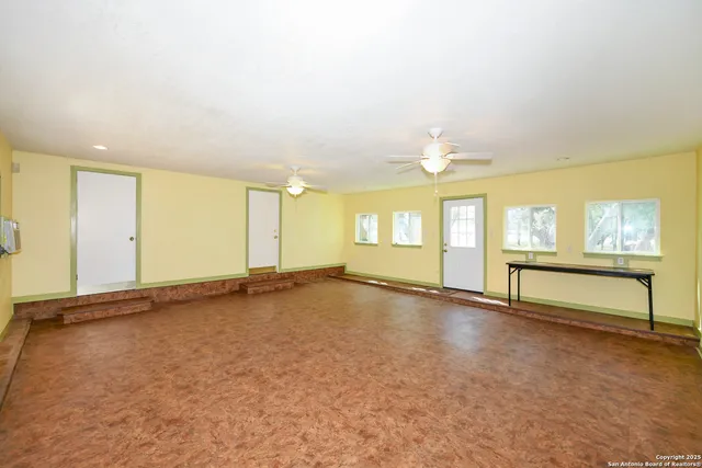 an empty room with windows and ceiling fan