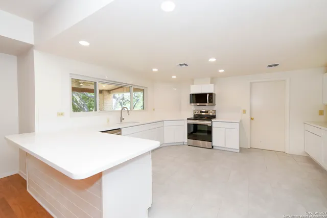 a kitchen with granite countertop a stove a sink and a microwave