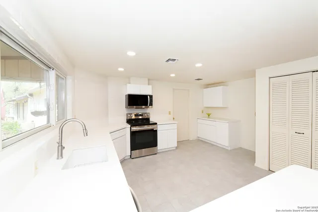 a kitchen with stainless steel appliances a sink a stove top oven a counter space and cabinets