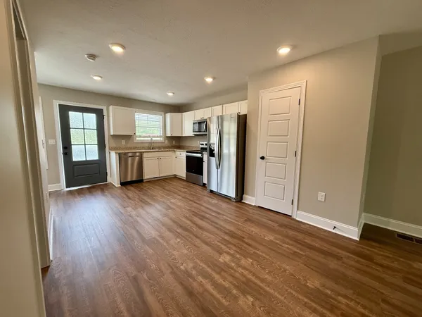 a view of a kitchen with refrigerator stove and wooden floor