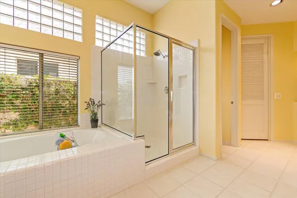 a bathroom with a tub shower and window