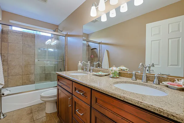 a bathroom with a granite countertop sink a toilet a mirror and shower