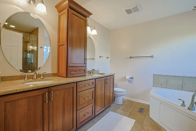a bathroom with a granite countertop sink mirror vanity and toilet