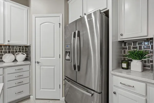 a large white kitchen with a refrigerator a stove a dining table and chairs