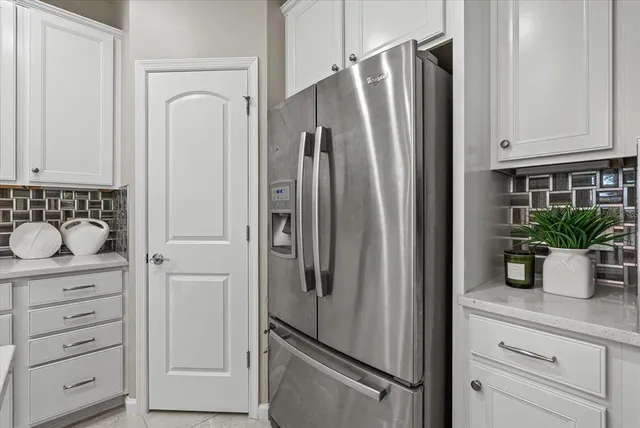 a large white kitchen with a refrigerator a stove a dining table and chairs