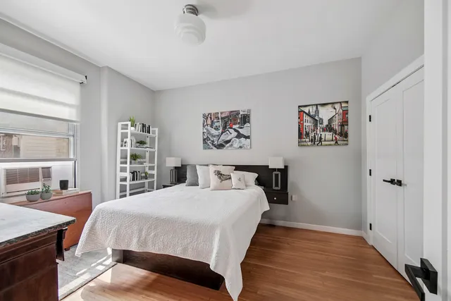 a bedroom with a large bed a painting on the wall and a window