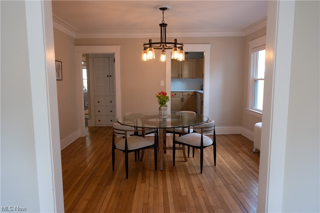 2135 Renrock Road Cleveland, OH 44118 - Photo 7 of 44 Dining space featuring radiator heating unit, ornamental molding, light wood-type flooring, and a notable chandelier