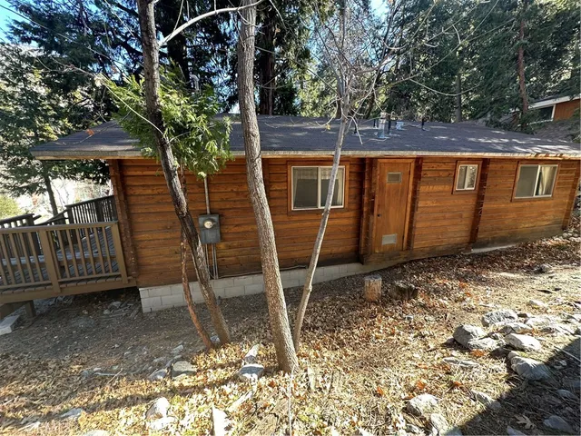 a view of a wooden house with a large window and wooden fence