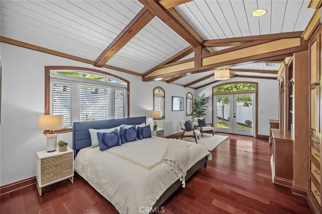 a spacious bedroom with wooden floors a bed and a chandelier