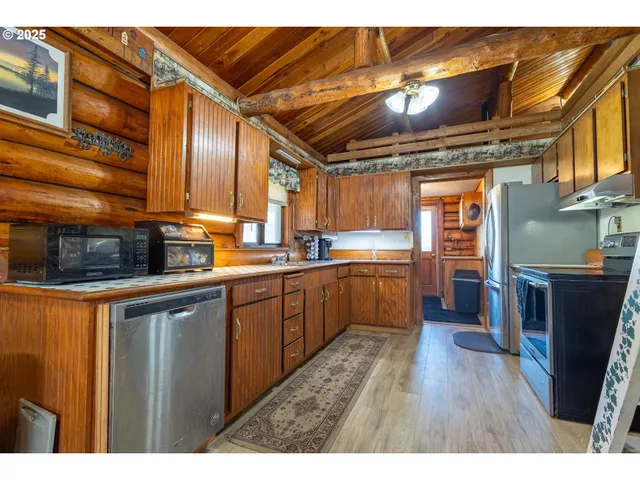 a kitchen with stainless steel appliances granite countertop a refrigerator a sink dishwasher a stove and white countertops with wooden floor