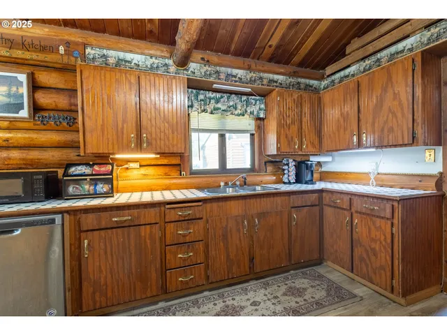 a kitchen with stainless steel appliances granite countertop a sink window and cabinets