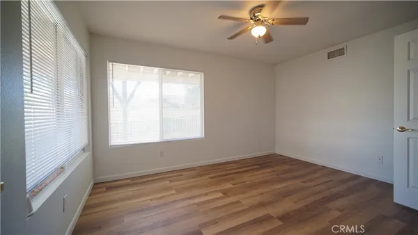 a view of empty room with wooden floor and fan