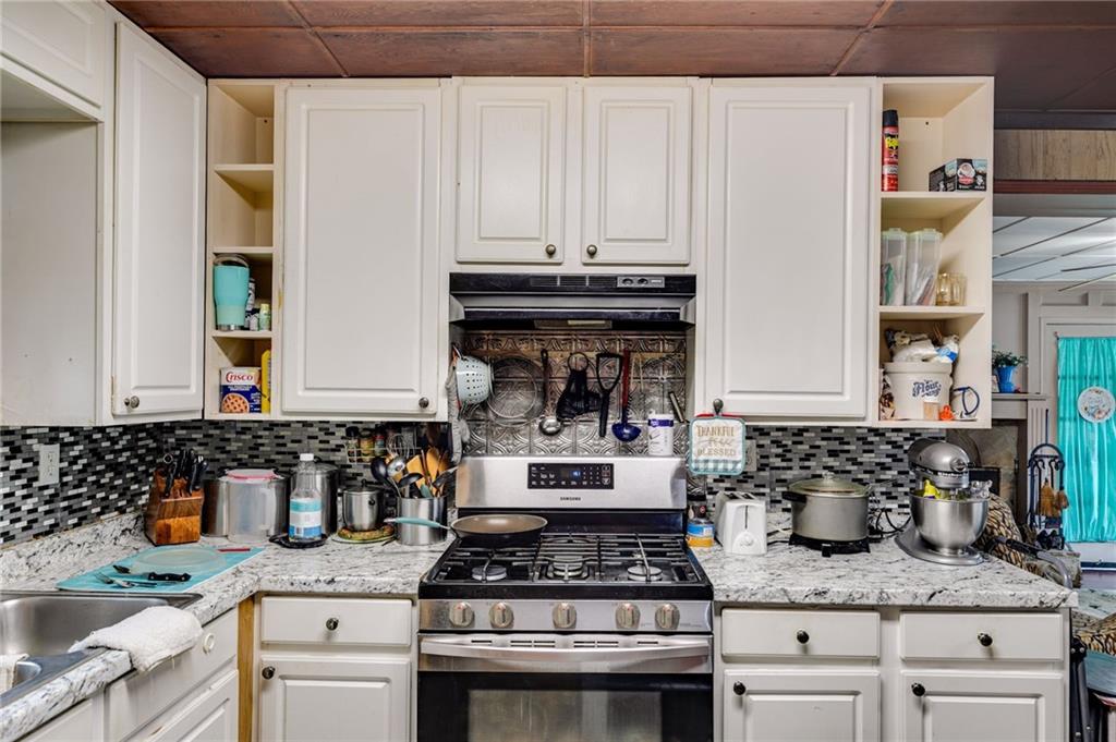 4661 Fowler Street Acworth, GA 30101 - Photo 8 of 16 a kitchen with granite countertop a stove a sink and white cabinets