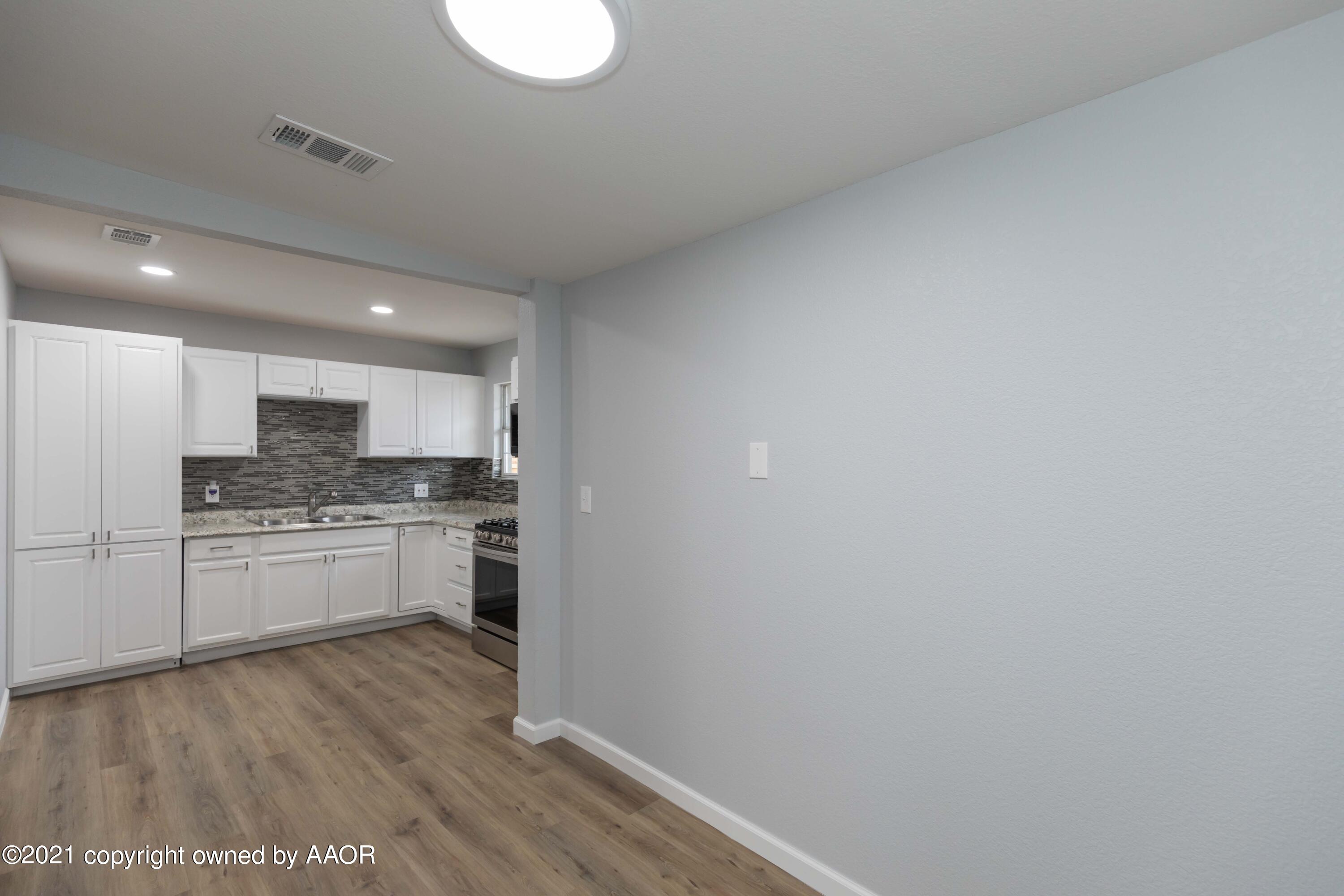 3808 Gables Street Amarillo, TX 79110 - Photo 10 of 23 a kitchen with kitchen island a sink wooden floor and white stainless steel appliances