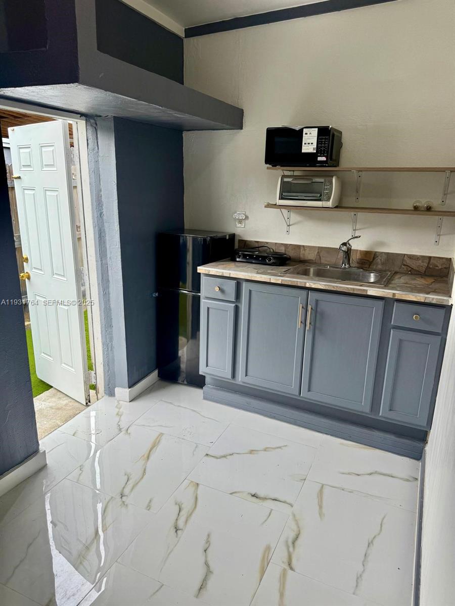 10357 Southwest 174th Terrace, Unit 1 Miami, FL 33157 - Photo 4 of 7 a kitchen with stainless steel appliances granite countertop a refrigerator sink and microwave