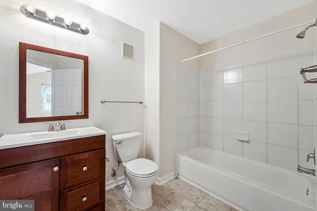 a bathroom with a bathtub shower sink vanity mirror and toilet