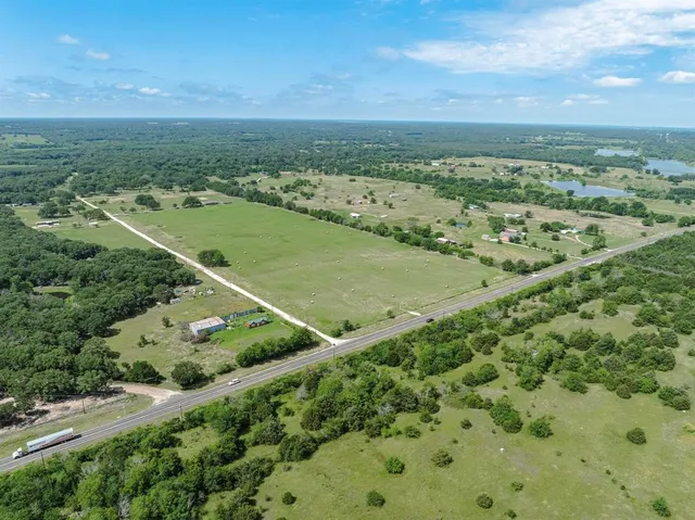 an aerial view of a residential houses with outdoor space and trees