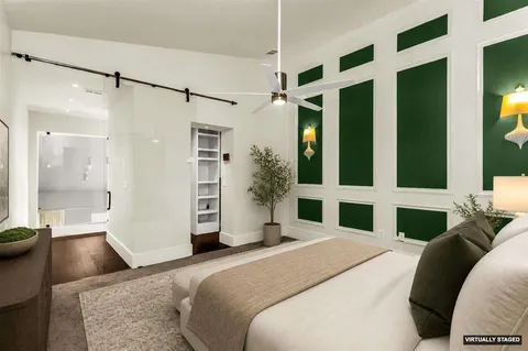 a bedroom with a bed and a large mirror with a wooden floor
