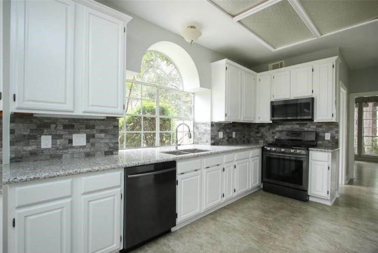 16222 Morningbrook Drive Spring, TX 77379 - Photo 13 of 44 a kitchen with stainless steel appliances granite countertop white cabinets granite counter tops and a window