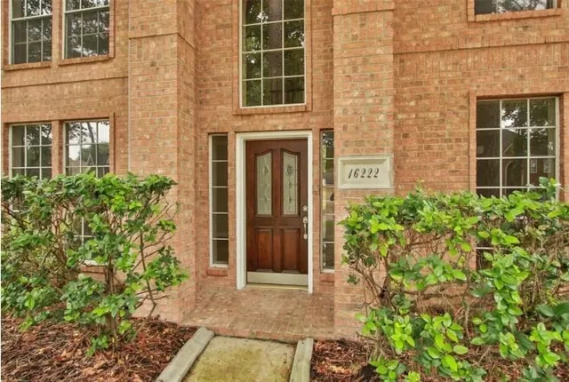 front view of a brick house with a large window and potted plants