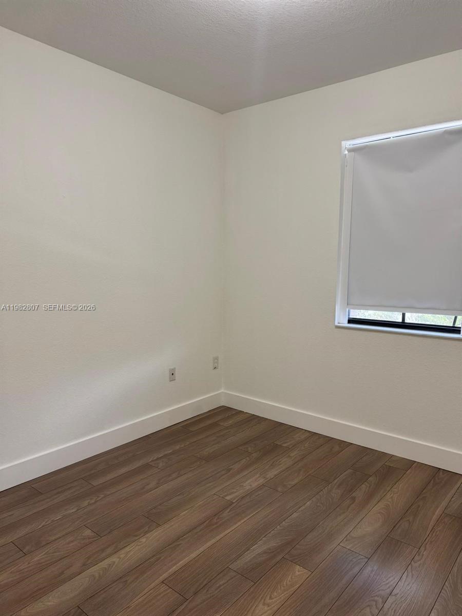 4217 Southwest 164th Court Miami, FL 33185 - Photo 14 of 15 a view of an empty room with wooden floor and a window