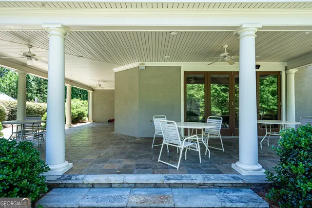 a patio with table and chairs and potted plants