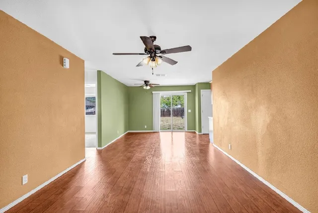 a view of a big room with wooden floor and a chandelier fan in a room