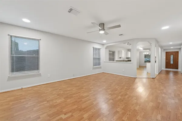 a view of an empty room with a window and wooden floor