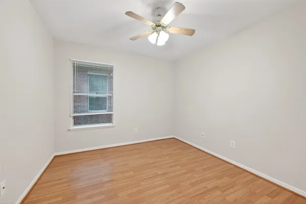 an empty room with a window and a fan