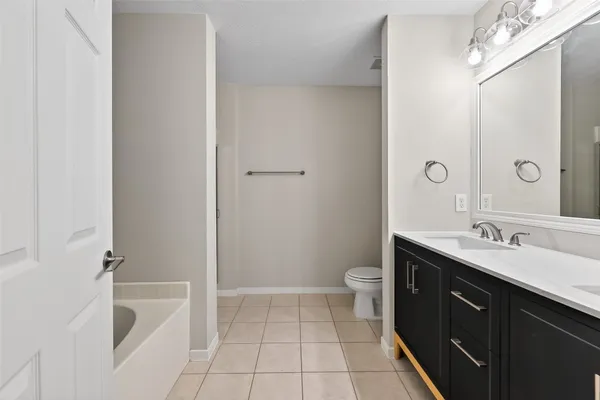 a spacious bathroom with a granite countertop sink a toilet mirror and shower