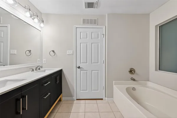 a spacious bathroom with a tub sink shower and mirror