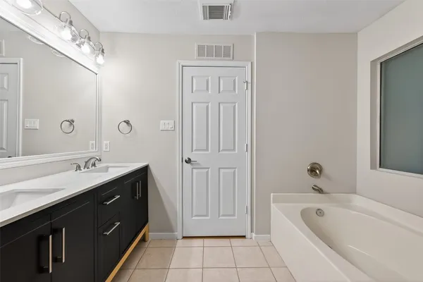 a spacious bathroom with a tub sink shower and mirror