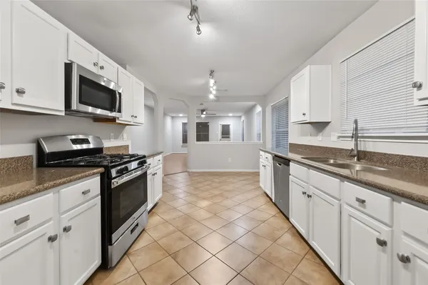 a large kitchen with stainless steel appliances granite countertop a sink and dishwasher a stove top oven with white cabinets