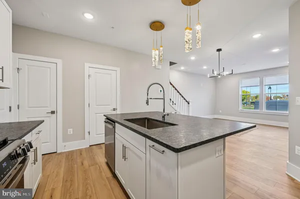 a kitchen that has a sink a microwave oven a stove and white cabinets with wooden floor